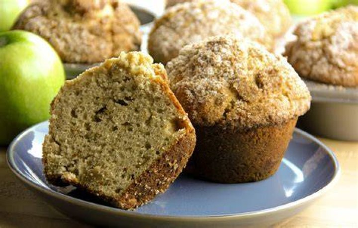 Apple cinnamon muffin cut in half and topped with butter.