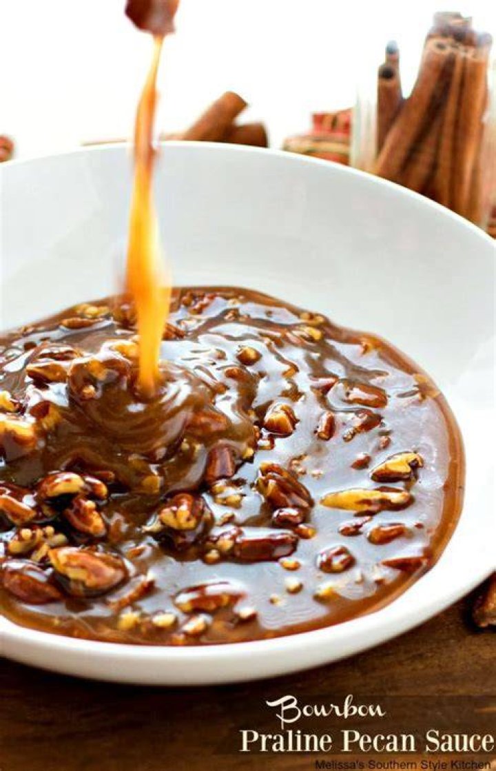Bowl of caramel pecan sauce with biscuit dough in the background.