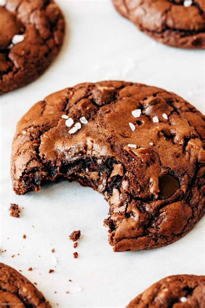 Brownie cookies on a piece of parchment paper topped with flaky sea salt.