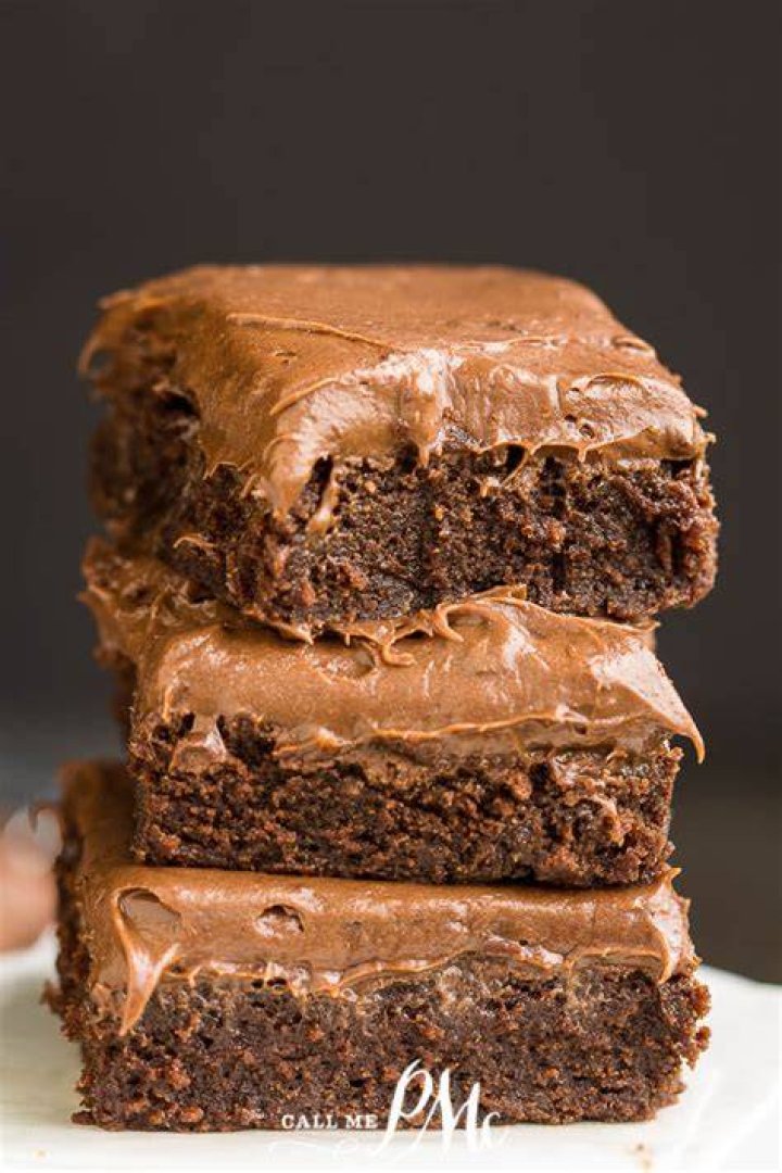 Brownies topped with chocolate icing in a white pan.