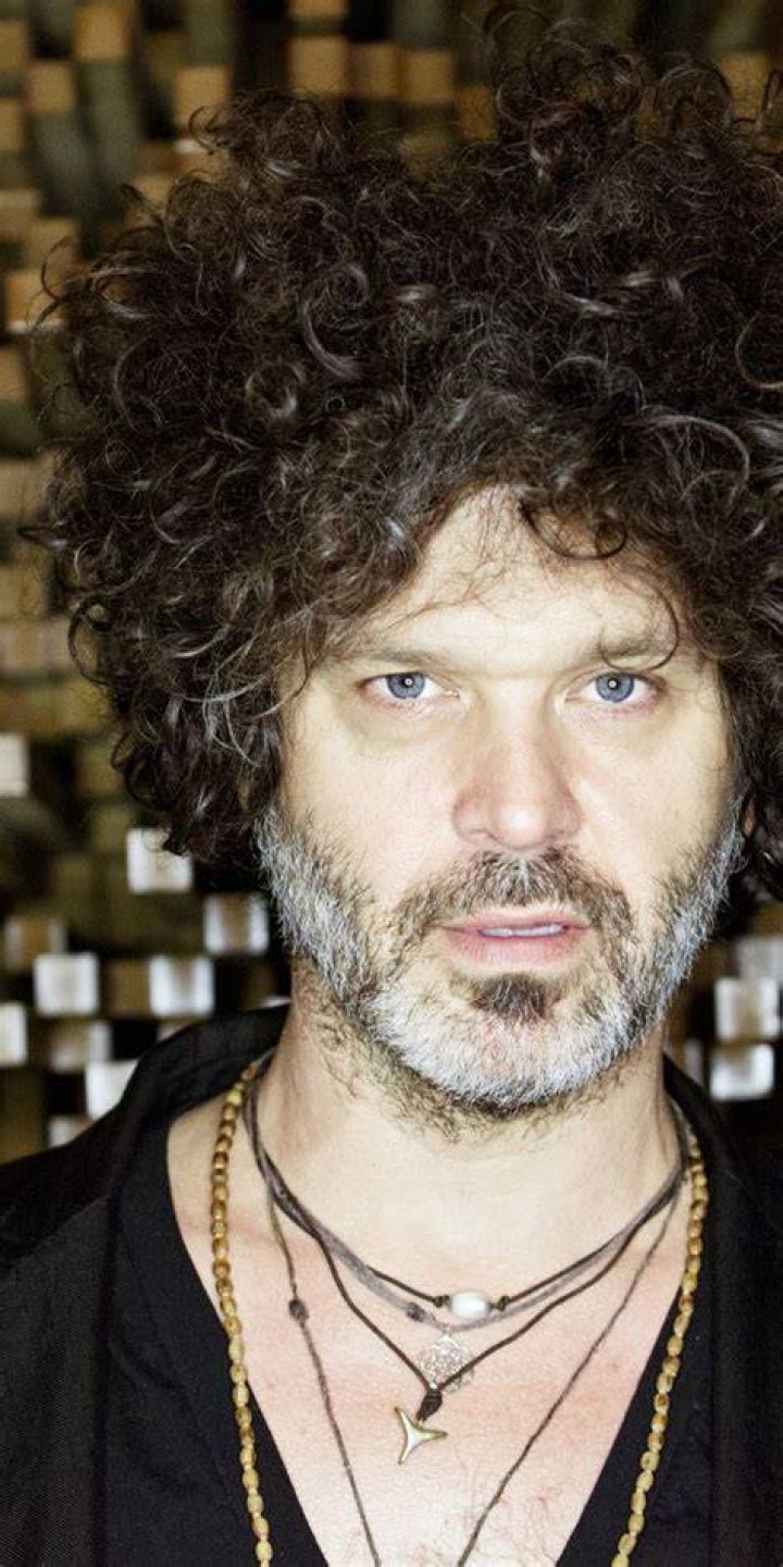 Doyle Bramhall in a black t-shirt holding his guitar.