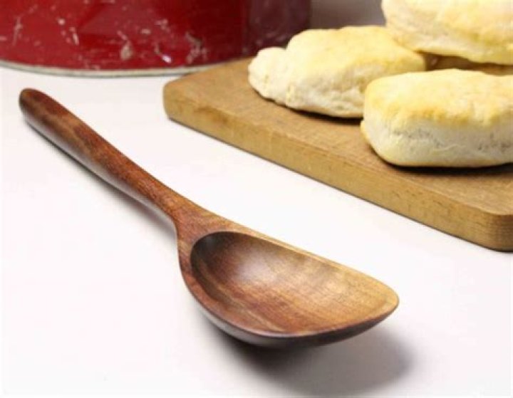 End of a wooden spoon being pushed into a ball of cookie dough.