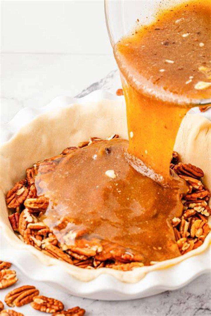 Pecan pie filling being scooped onto a sugar cookie.