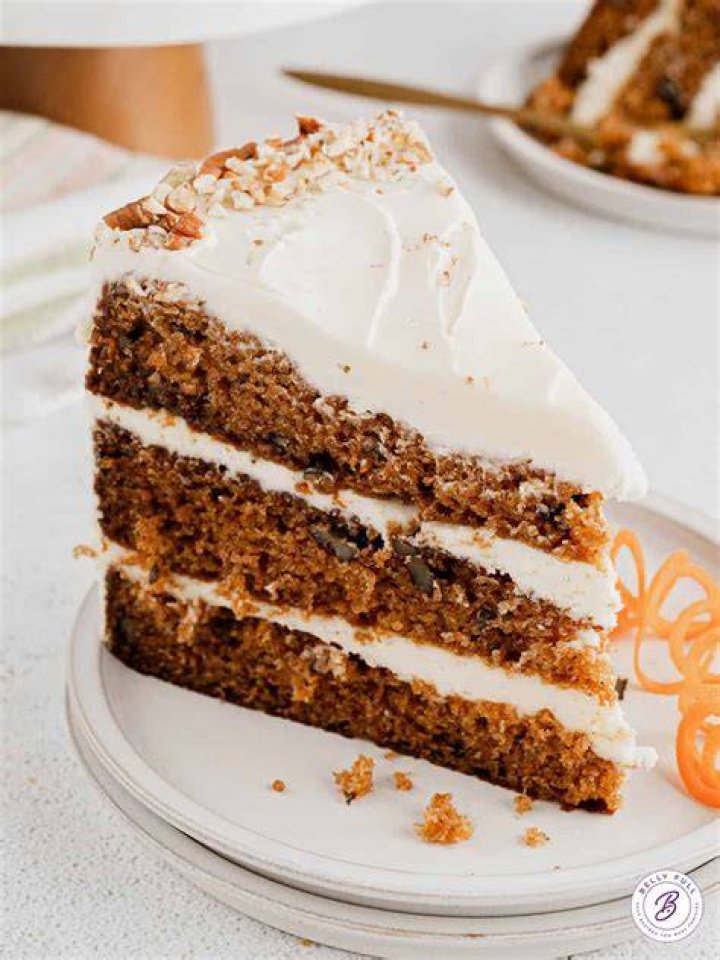 Slice of carrot cake on a wooden plate.