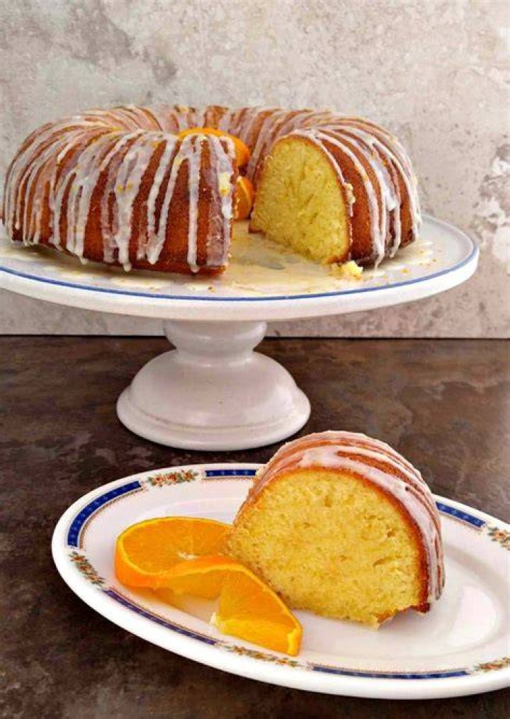 Slice of orange bundt cake on a white plate with a gold fork.