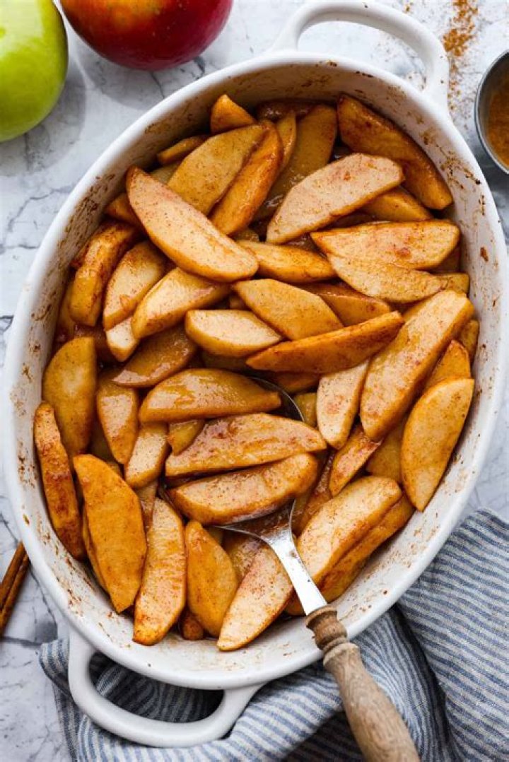 Sliced apples, cinnamon, and sugar in a glass bowl.