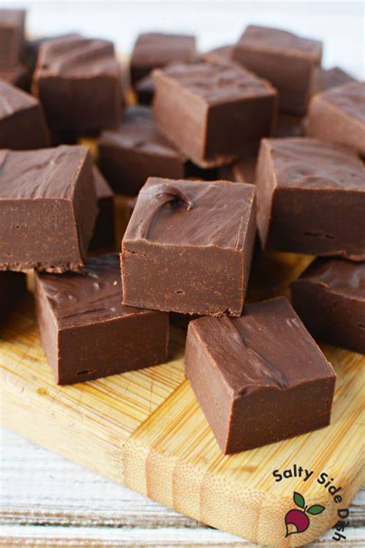 Slices of fudge on a silver plate topped marshmallows and crushed candy canes.
