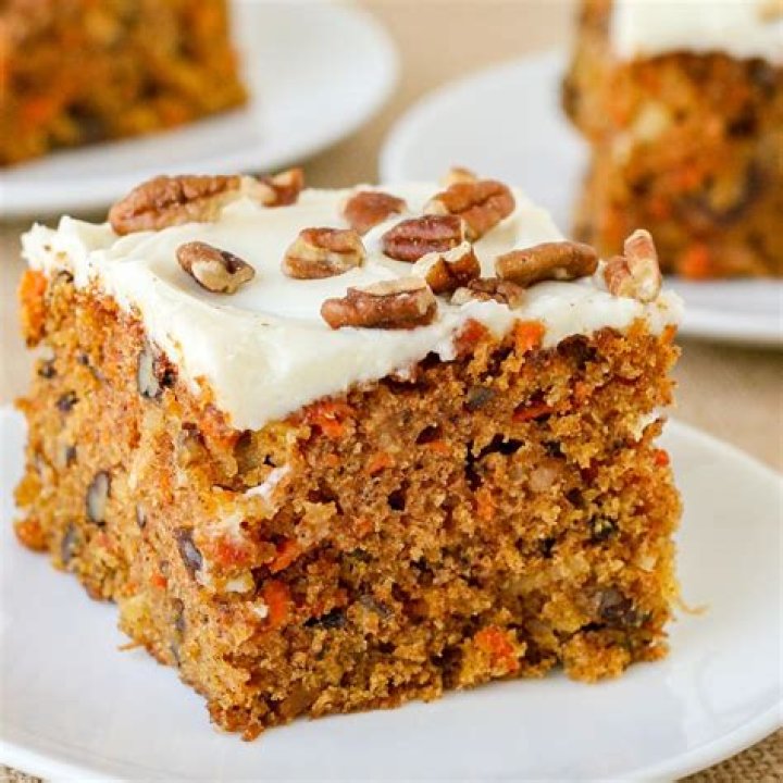 Square slice of carrot cake topped with white frosting.
