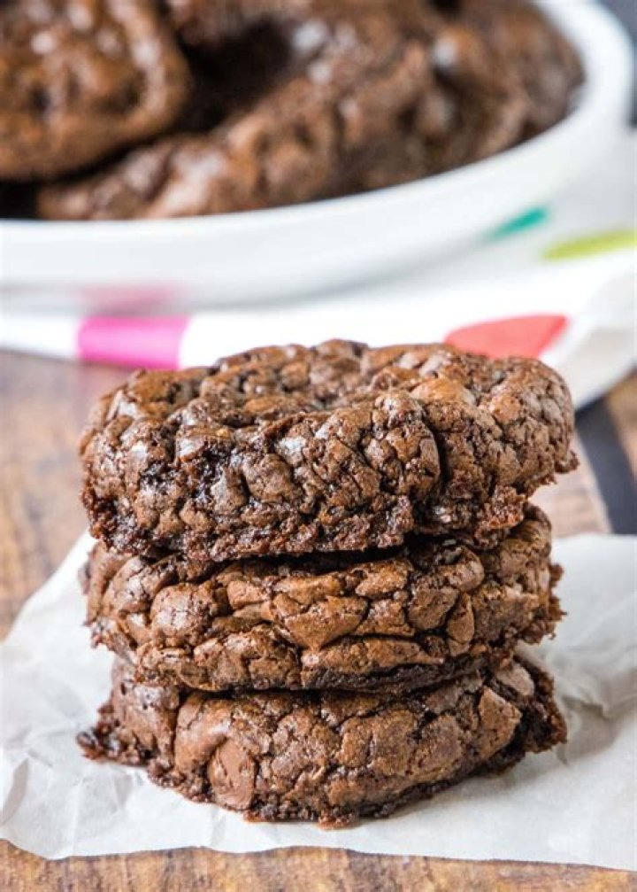 Stack of three brownie cookies with a bite taken out of the top cookie.