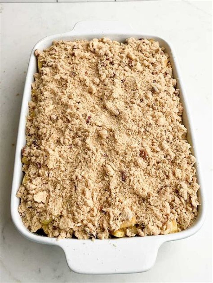 Unbaked apple crisp in a white circular baking dish.