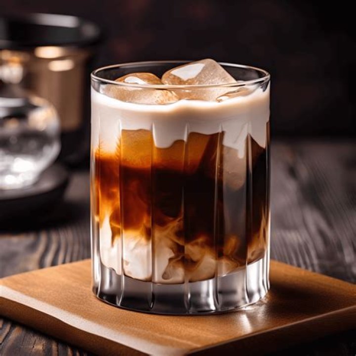 White russian cocktail in a glass with two gold spoons on the side. 